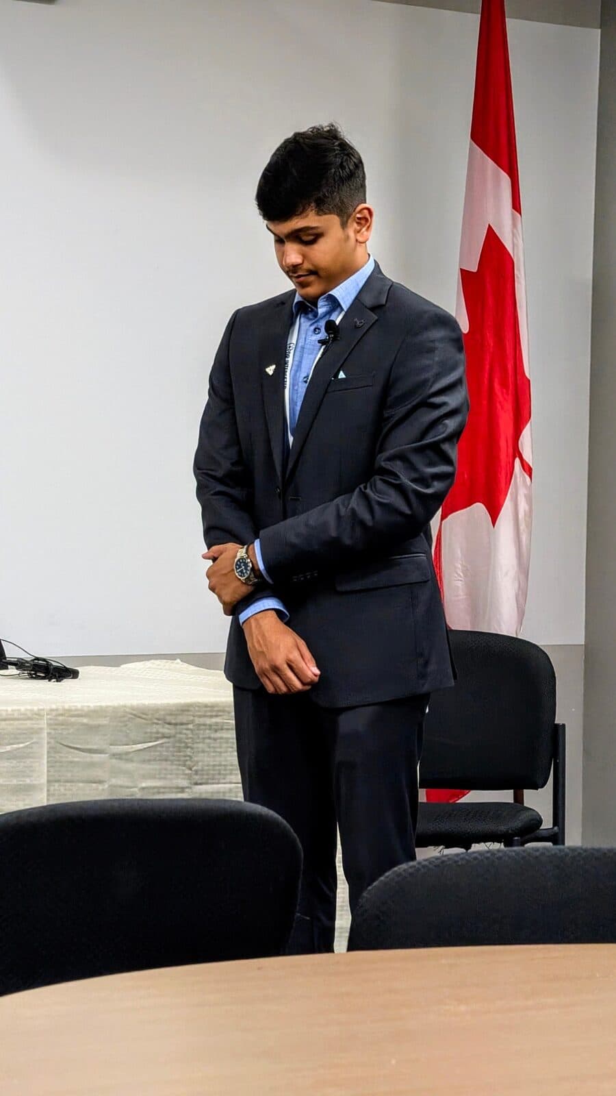 Adil Mukhi in a suit beside the Canadian flag