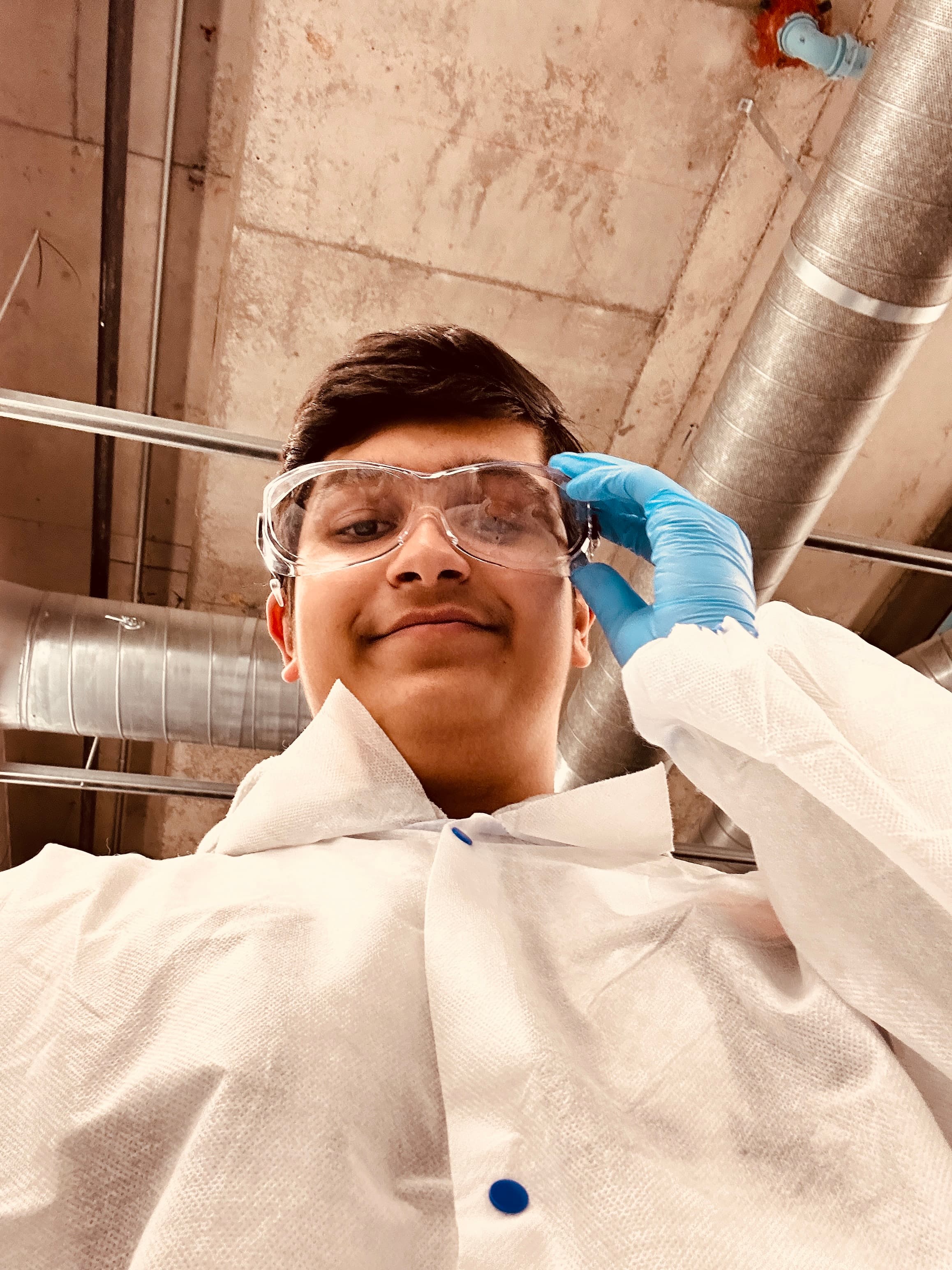 Adil Mukhi in a lab coat and safety glasses
