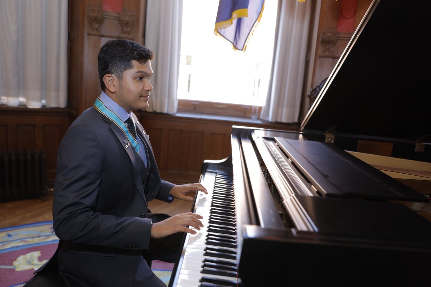 Adil Mukhi playing a grand piano at Queen's Park