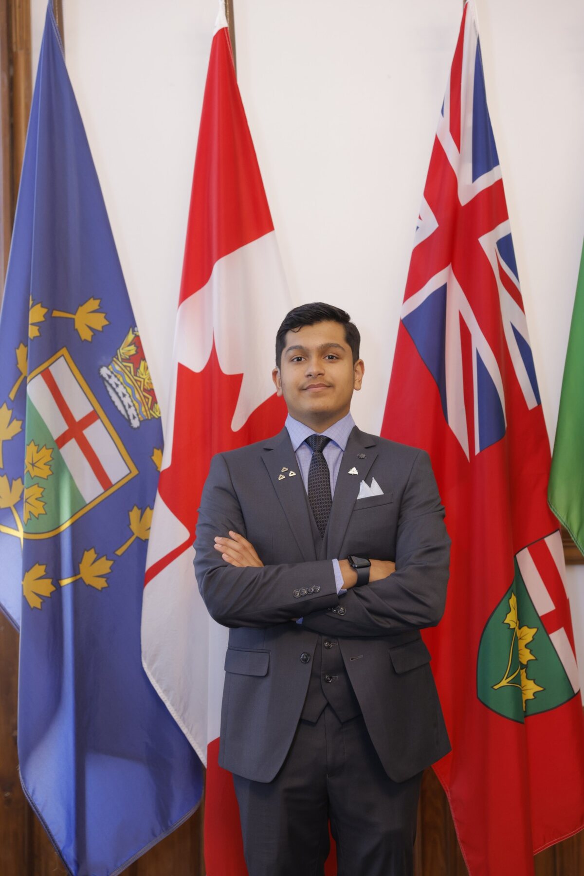 Adil Mukhi in a suit in front of the Canadian and Ontario flags